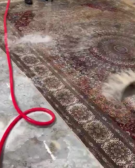 Tapis à médaillon en cours de lavage à l'atelier : la partie lavée retrouve ses couleurs